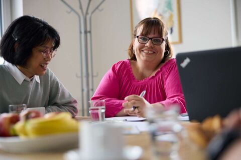 Frau blickt lächelnd in die Kamera. Neben ihr sitzt eine andere Frau (Foto: Lebenshilfe/David Maurer)