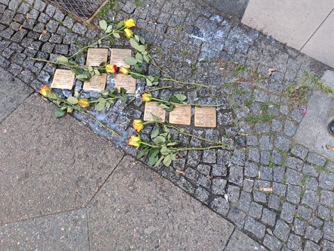 Geputzte Stolpersteine mit gelben Rosen in Neukoelln.