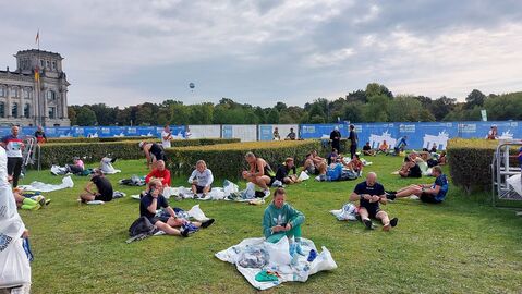 Erschöpfte Läufer:innen auf der Wiese nach dem Marathon